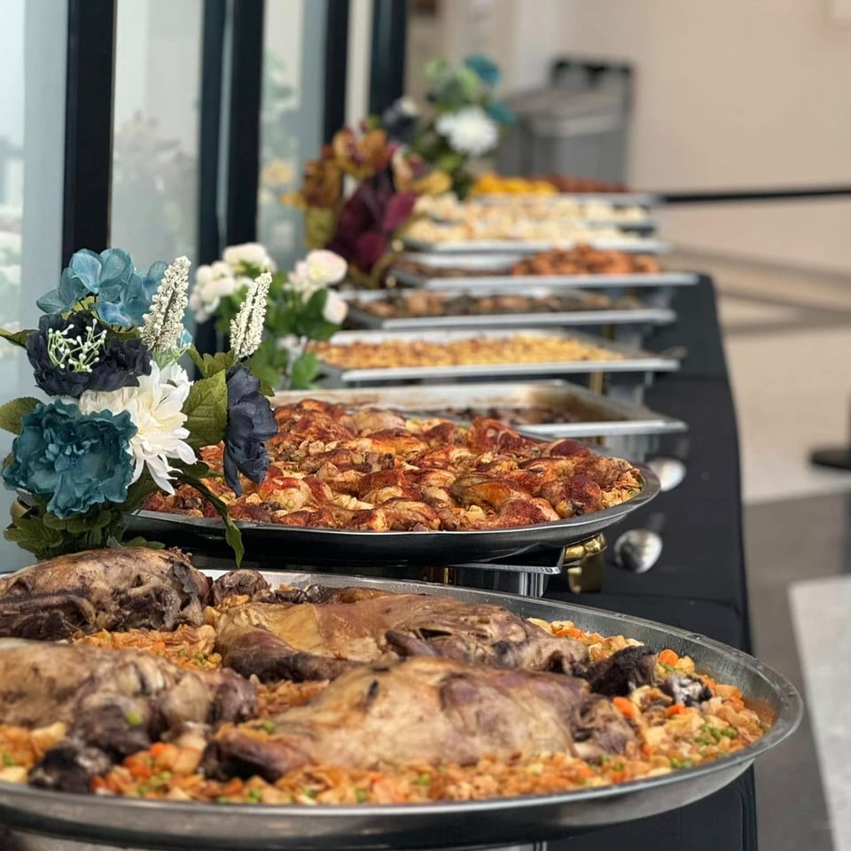 A buffet table laden with large platters of middle-eastern roasted meats and rice dishes.