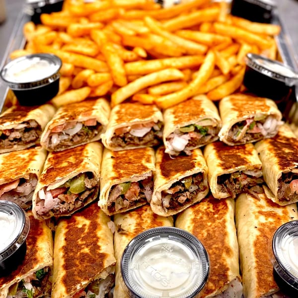 A tray of SK Shawarma wraps and golden french fries with dipping sauces.